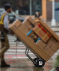 Person using hand truck with 4 Pack 10 Inch Tough As Nails Replacement Tire And Wheel For 4.10/3.50-4 on a rainy street.