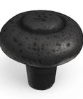 Single black iron knob from the Heavy Duty Solid Metal Core Cabinet Knobs 10 Pack Black Iron One And One Quarter Inch Hardware For Cabinets And Drawers Built To Last With Refined Rustic Collection For A Modern Rugged Vibe, showcasing top detail and texture.