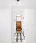 Cool Soft Black Semi Flush Mount Ceiling Light With Frosted Glass Shade in white hallway with geometric floor tiles