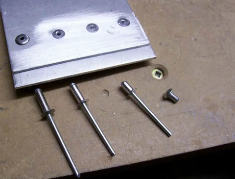 Size Forty Four Button Head Blind Rivets One Eighth Inch Diameter Three Sixteenths To Quarter Inch Grip Range Three Oh Four Stainless Steel Marine Grade Heavy Duty Fasteners Pops Tight Holds Strong For Rugged Outdoor Builds 100 Piece Pack on wooden surface with metal panel.