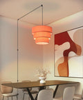 Orange Plug In Pendant Light With Three Tier Mid Century Modern Linen Shades Stylish Hanging Chandelier above a dining table.