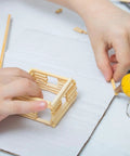 Child assembling a model house with Premium Unfinished Birch Dowel Rods 1/4 X 6 In Natural Hardwood Sticks for Crafts.