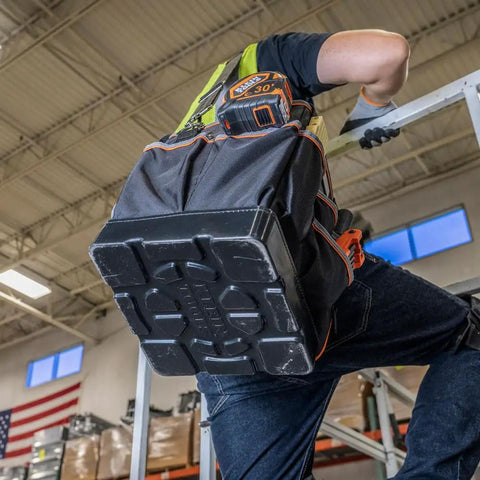 Person climbing ladder with Heavy Duty Tool Bag With Shoulder Strap And 40 Pockets In Bright Orange Interior For Fast Tool Access