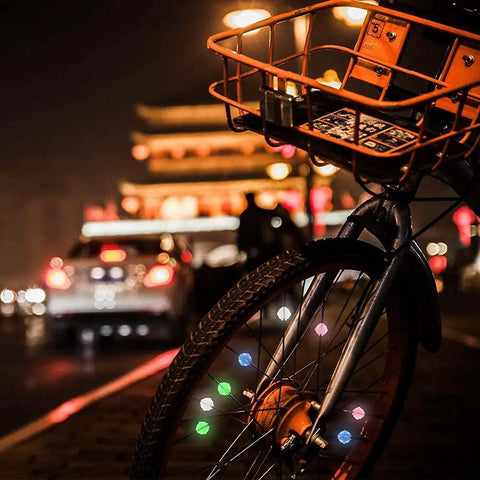 Bicycle wheel with Multicolor Bicycle Spoke Beads Set With Luminous Plastic Clips at night, creating a vibrant look