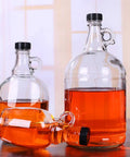 12 Pack 38mm Growler Caps With Durable Poly Seal Lids for Half Gallon and One Gallon Glass Jugs Replacement Tops for Homebrew Beer and Wine Making For Your Brew Scene Black, shown sealing orange liquid in glass jugs of varying sizes.