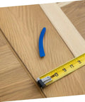 Wooden floorboard transition with a blue spacer and measuring tape