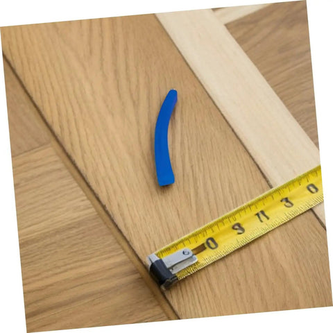Wooden floorboard transition with a blue spacer and measuring tape
