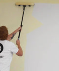 Painting a wall with the Pro Grade 20 Piece Paint Roller Set With Adjustable Frame And Extension Pole, using a long handle roller.