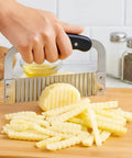 HIC Kitchen crinkle-cut wave slicer with stainless steel blade cutting potatoes into waffle fries on a wooden board
