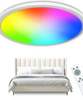 RGB LED Ceiling Light 12 Inch, 24W 5000K Dimmable Flush Mount with Remote above bed displaying rainbow colors.