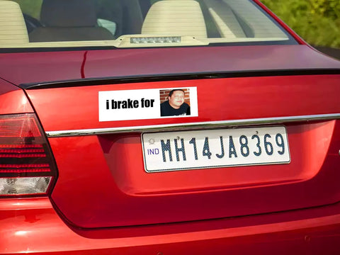 Rear view bumper sticker magnet, white with i brake for text and small portrait photo on red car.