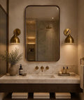 Mid Century Modern Brass Wall Sconces Set of 2 above a marble sink in a stylish bathroom with natural decor.