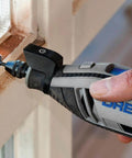 Side view of a Dremel rotary tool with 1/2-inch coarse sanding bands attached, sanding a wooden window frame.