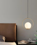 Mid Century Modern Large Globe Pendant Light With Brushed Brass Finish And White Glass Sphere hanging beside bed