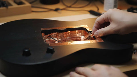 Applying High Conductivity Copper Foil Tape For Guitar EMI Shielding inside a guitar cavity to reduce interference in home audio projects.