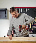 Person using Heavy Duty Cordless Drill And Screwdriver 18 Volt Brushless Motor 50 Nm Built Tough on wooden plank in workshop.