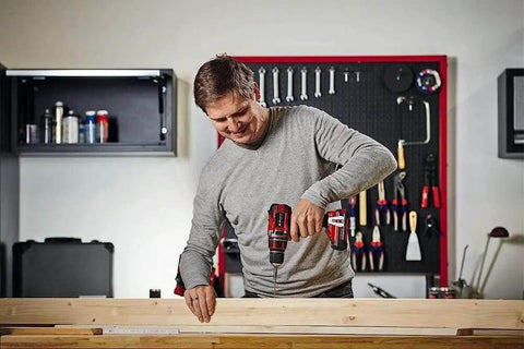 Person using Heavy Duty Cordless Drill And Screwdriver 18 Volt Brushless Motor 50 Nm Built Tough on wooden plank in workshop.