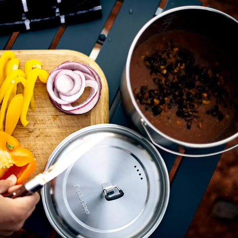 Two Pot Stainless Steel Camp Stove Set With Three Liter And One And A Half Liter Pots, Vent Holes And Silicone Coated Tabs For Easy Release, Ideal For Backpacking, Camping, And Survival Cooking, showing ingredients being prepared and stew in pot