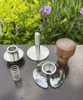 Top Tier 51mm Stainless Steel Coffee Tamper With Adjustable Calibration And Anti Deviation Base, disassembled parts on a table.