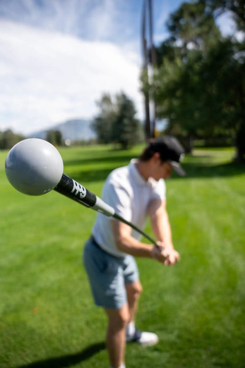 Golfer using Pin Point Golf Swing Tempo Trainer And Warm Up Club With Flexible Shaft For Lag Training, Black, on grass.