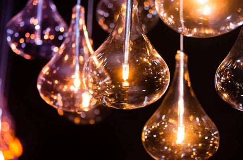 Close-up of illuminated GY6.35 50W dimmable halogen bulbs 12V warm white 2700K in decorative teardrop glass fixtures at night.