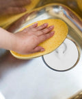 4pcs Rubber Sink Drain Stopper with Pull Ring for Bathtubs shown in use, with a sponge and hand pressing on the sink's drain.