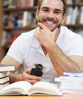 Man holding smartphone with upgraded Bluetooth barcode scanner with back clip in library setting surrounded by books.