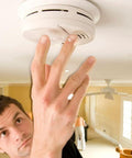 Person testing No Hassle Hardwired Smoke Detector With Front Load Battery Backup And Smooth One Touch Test Button For Reliable Home Safety.