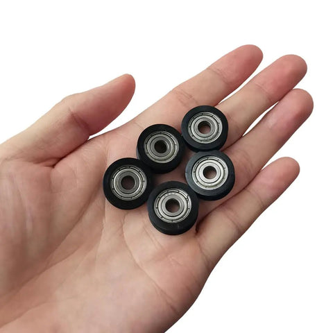 Five Badass U Groove Ball Bearings 5mm Double Shielded Chromium Steel V Track Rollers in hand for precision use.