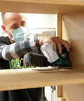 User using 18V Cordless 1/4 Sheet Finishing Sander With Two Speed Control 11K And 14K OPM Uses Four And A Half Inch By Four Inch Abrasive Paper Large Clamping Lever Tool Only on wooden shelf during a project.