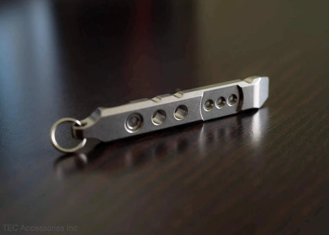 Close-up of Titanium Ti Pry Mini Pry Bar Keychain EDC Pocket Pry Tool With Bottle Opener, 6Al4V titanium construction on a table.