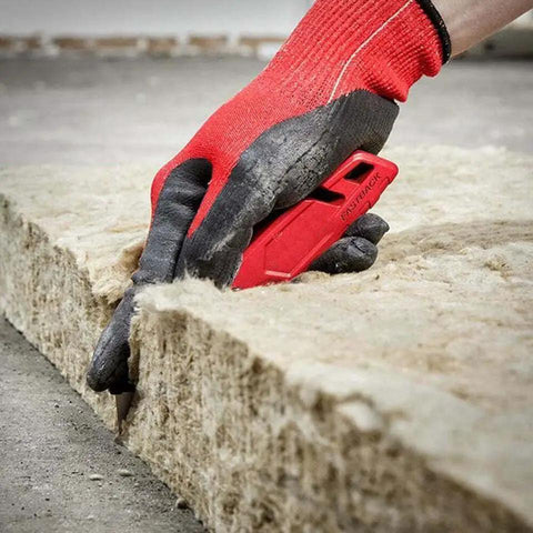 Hand using Compatible With Milwaukee Fastback Utility Knife Model 48 22 1502 to cut insulation with red handle on construction site.