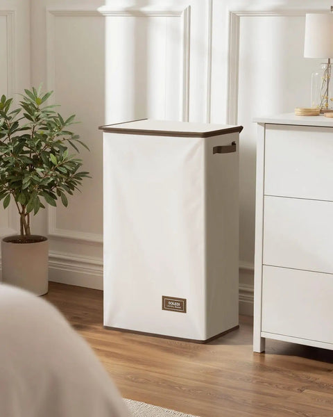 Big Ol 100L Large Laundry Basket With Removable Bag And Lid in bedroom setting, off white color, sturdy and collapsible.