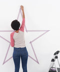 Person applying Delicate Surface Painter Tape 0.94 Inch By 60 Yard Damage Free Prep For Painting Protect Delicate Surfaces on wall star