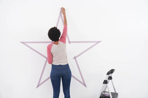 Person applying Delicate Surface Painter Tape 0.94 Inch By 60 Yard Damage Free Prep For Painting Protect Delicate Surfaces on wall star