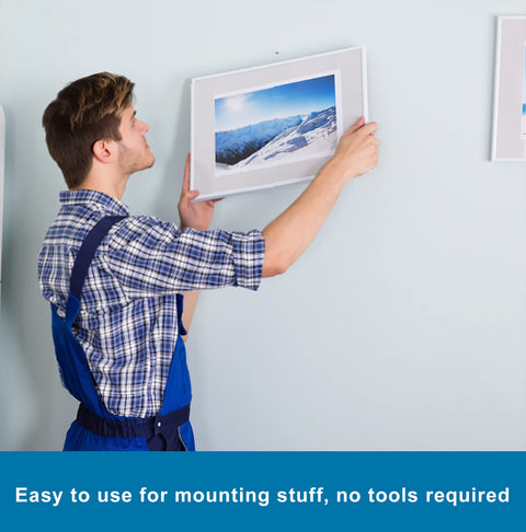 Person hanging a picture using Heavy Duty Double Sided Mounting Tape for Picture Hanging and Wall Art, no nails needed.