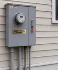 Electrical panel box mounted on house exterior with gold label, showing multiple conduits connected at the bottom.