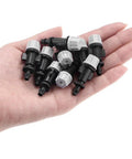 Hand holding multiple pieces of the 50 Piece Misting Nozzle Set for garden drip irrigation, durable plastic construction.