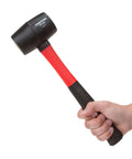 Hand holding 16 Oz Rubber Mallet With Fiberglass Handle Double Faced Solid Head Vibration Dampening Core Poly Jacket Protection