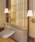 Two Pack Hardwired Brushed Brass Wall Sconces With Fabric Shade, mounted above a bed, modern classic lighting in a bedroom