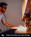 Dubofu laser safety goggles with black frame and dark lenses, worn by man beside a laser engraver emitting sparks