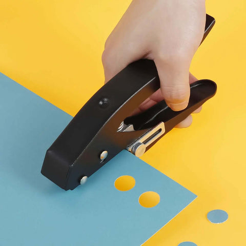 Hand using Heavy Duty 15 mm Round Hole Punch Tool For Paper, 20 Sheets Capacity, crafting precise circle holes on blue paper.