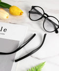 DIY Glasses Temple Replacement Arms Kit With Screws, Washers, Screwdriver And Nose Pads TR90 Eyeglasses Repair Set In Black. Includes black TR90 arms next to eyeglasses on a marble surface.