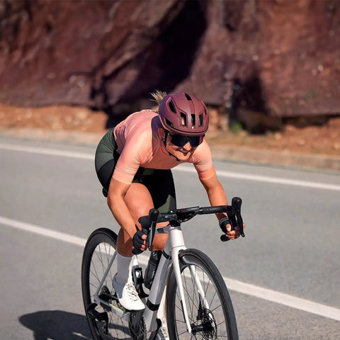 Cyclist on road using Edge 1050 Premium Cycling Computer Bundle With Color Touchscreen and speaker, wearing helmet.