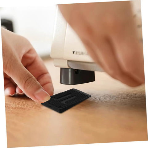 Person placing a black shim from the 20Pcs Furniture Leveling Shims Set under a table leg to stabilize on an uneven surface. No Fuss Quick Install.