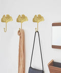 Ginkgo Leaf Wall Hooks Four Piece Iron Gold Key Holder And Hat Hanger in use, holding a scarf and bag on a white wall.