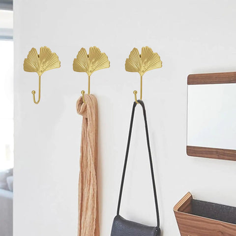 Ginkgo Leaf Wall Hooks Four Piece Iron Gold Key Holder And Hat Hanger in use, holding a scarf and bag on a white wall.