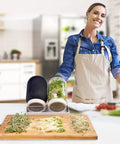 Woman using All In One Sprouting Jar Kit With Two Wide Mouth Mason Jars 316 Screen Sprout Lids Blackout Sleeves Tray And Stand For Growing Broccoli And Alfalfa At Home Seeds Not Included in kitchen.
