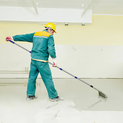 Worker using 20-inch spiked screeding roller for epoxy flooring with 2m detachable pole, achieving smooth finish.