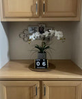 Wooden cupboard with gold and black knurled bar cabinet pulls, displaying a floral arrangement and decorative accents.